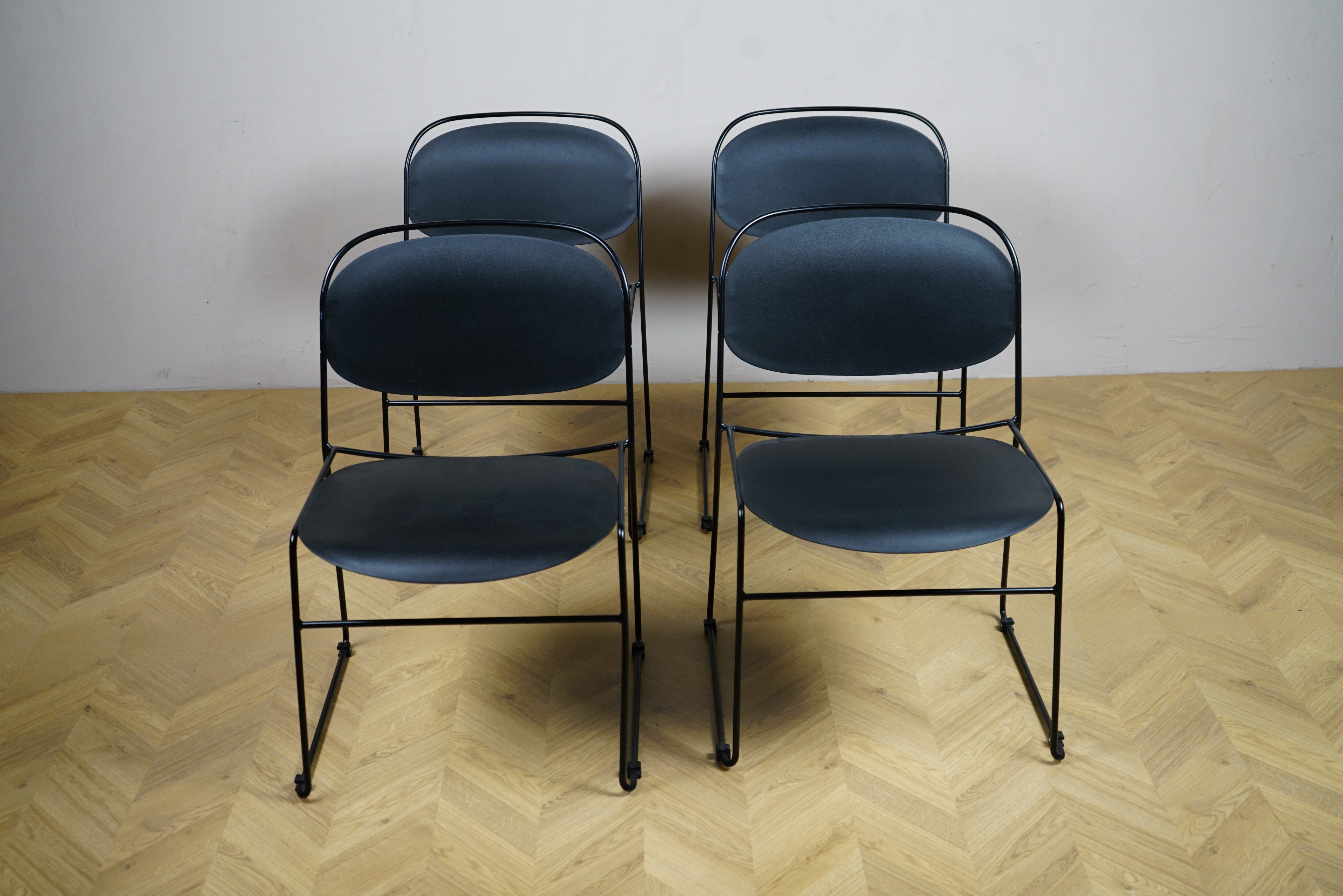 Sæt med 4 sorte Kinnarps stole set forfra – minimalistiske og stabelbare stole med 45 cm siddehøjde til spisebord eller mødelokale.